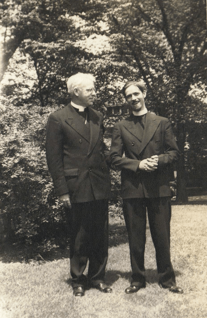 Alan Watts stands with a priest.