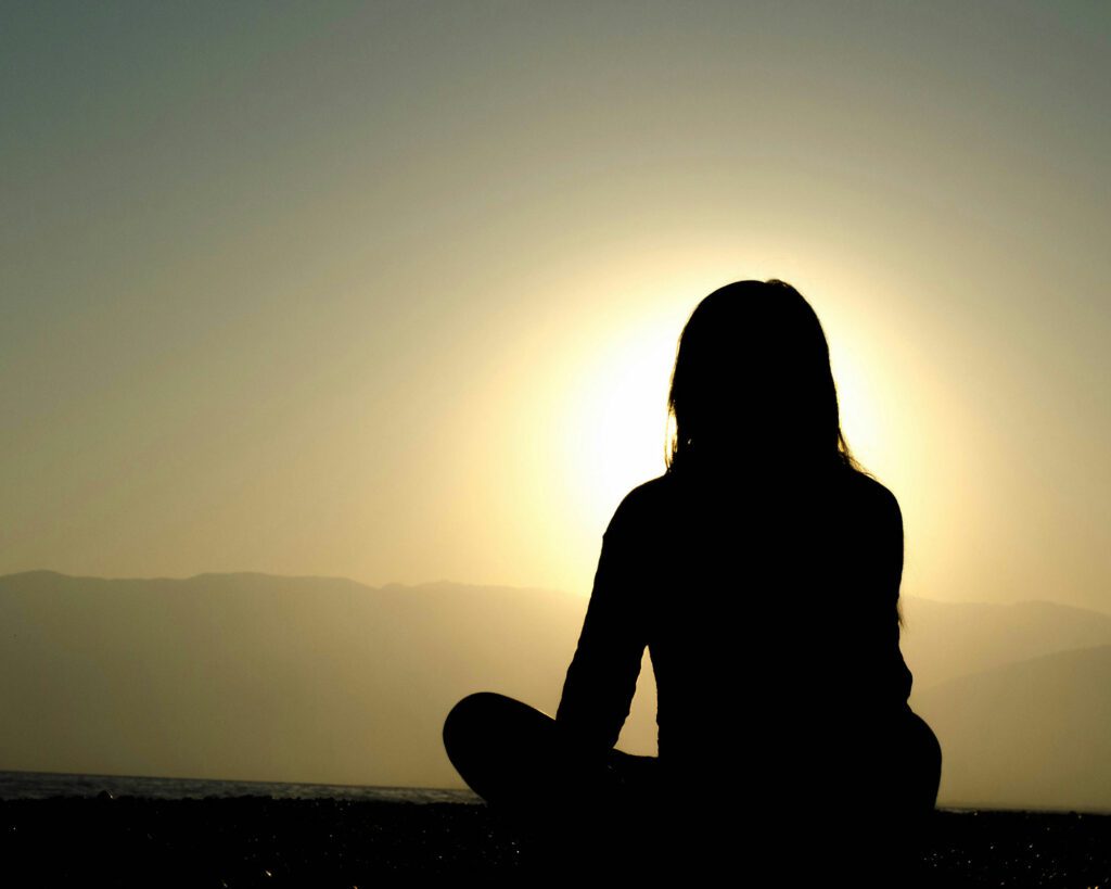 Image of a woman's silhouette on a hill, overlooking a city.
