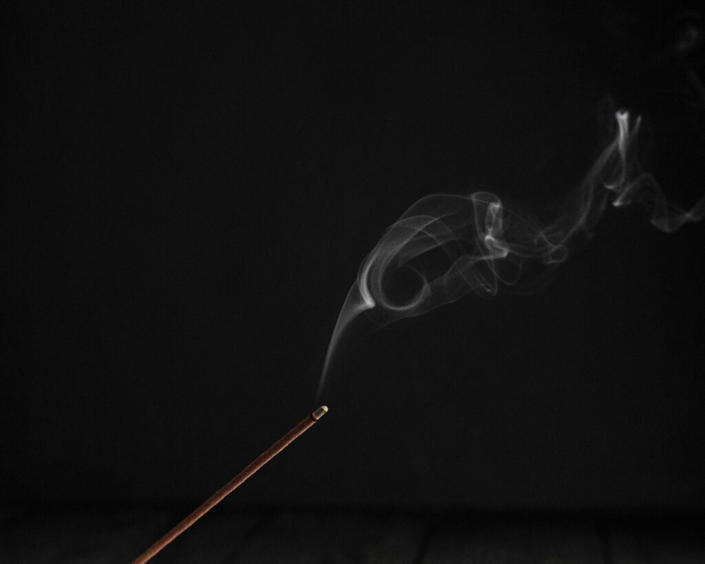 Image of a burning incense on dark background.