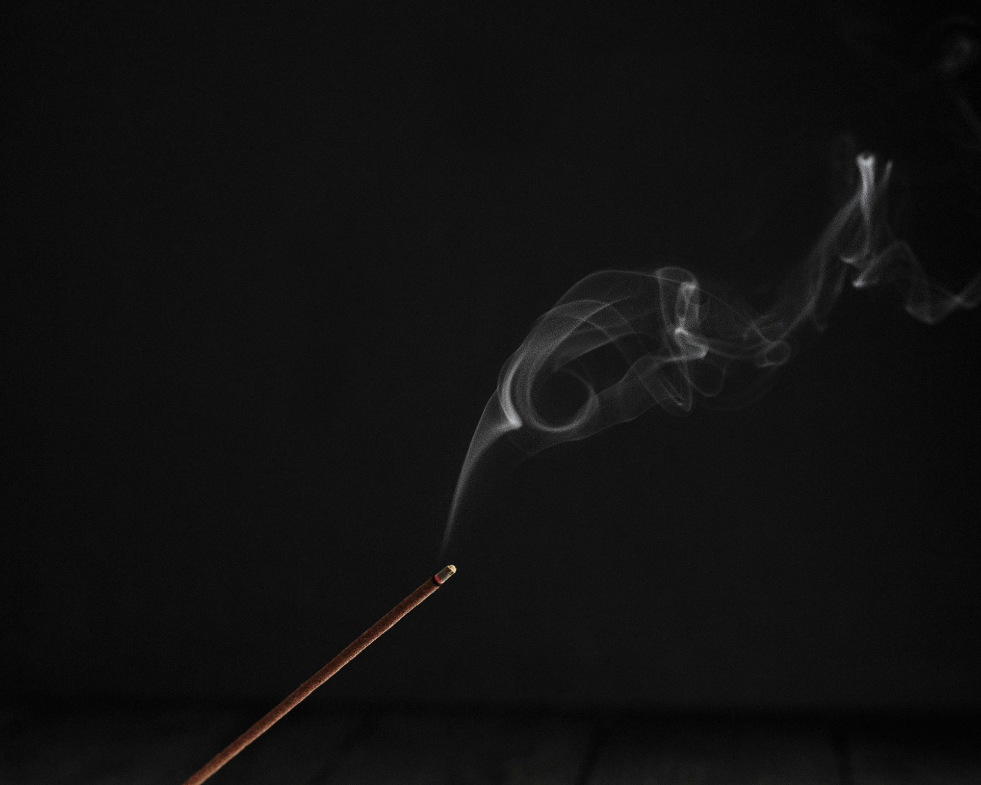 Image of a burning incense on dark background.