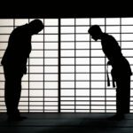 Two figures bow towards each other