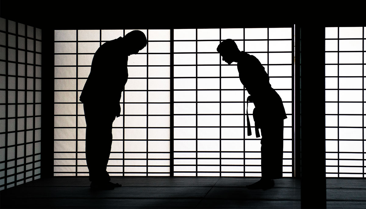 Two figures bow towards each other