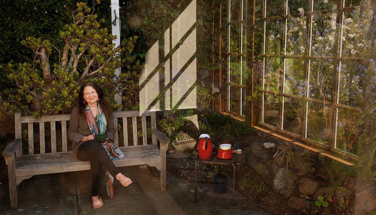 Jane Hirshfield sitting in sunroom on a bench