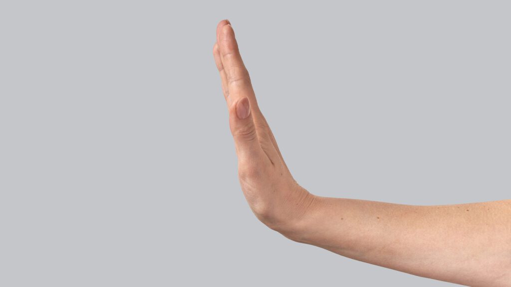 A hand extends in the "stop" gesture on a grey background