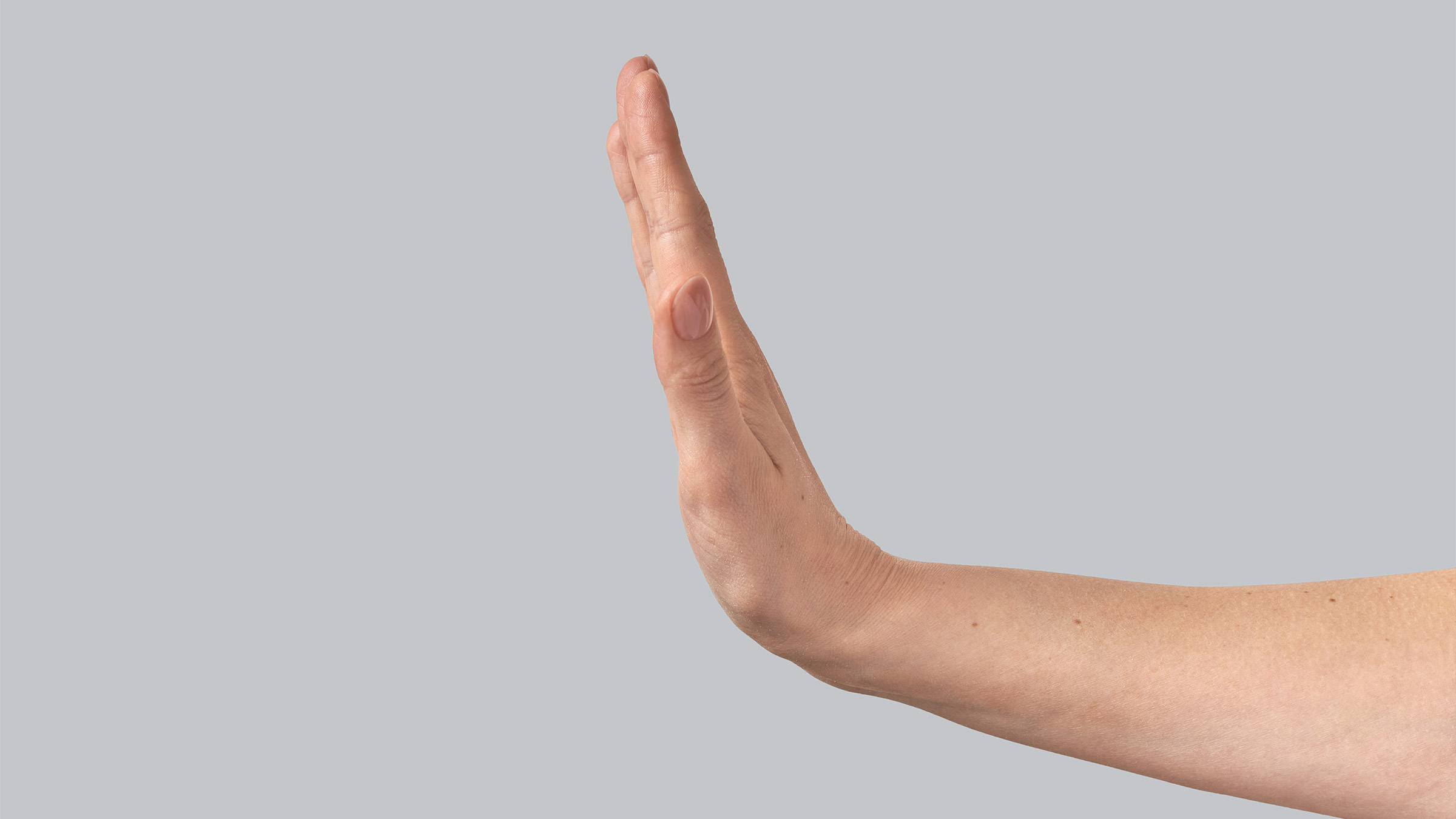 A hand extends in the "stop" gesture on a grey background
