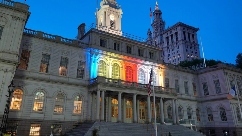 New York City Hall lit up in blue, yellow, red, white, and orange — the colors of the Buddhist flag — for Vesak.