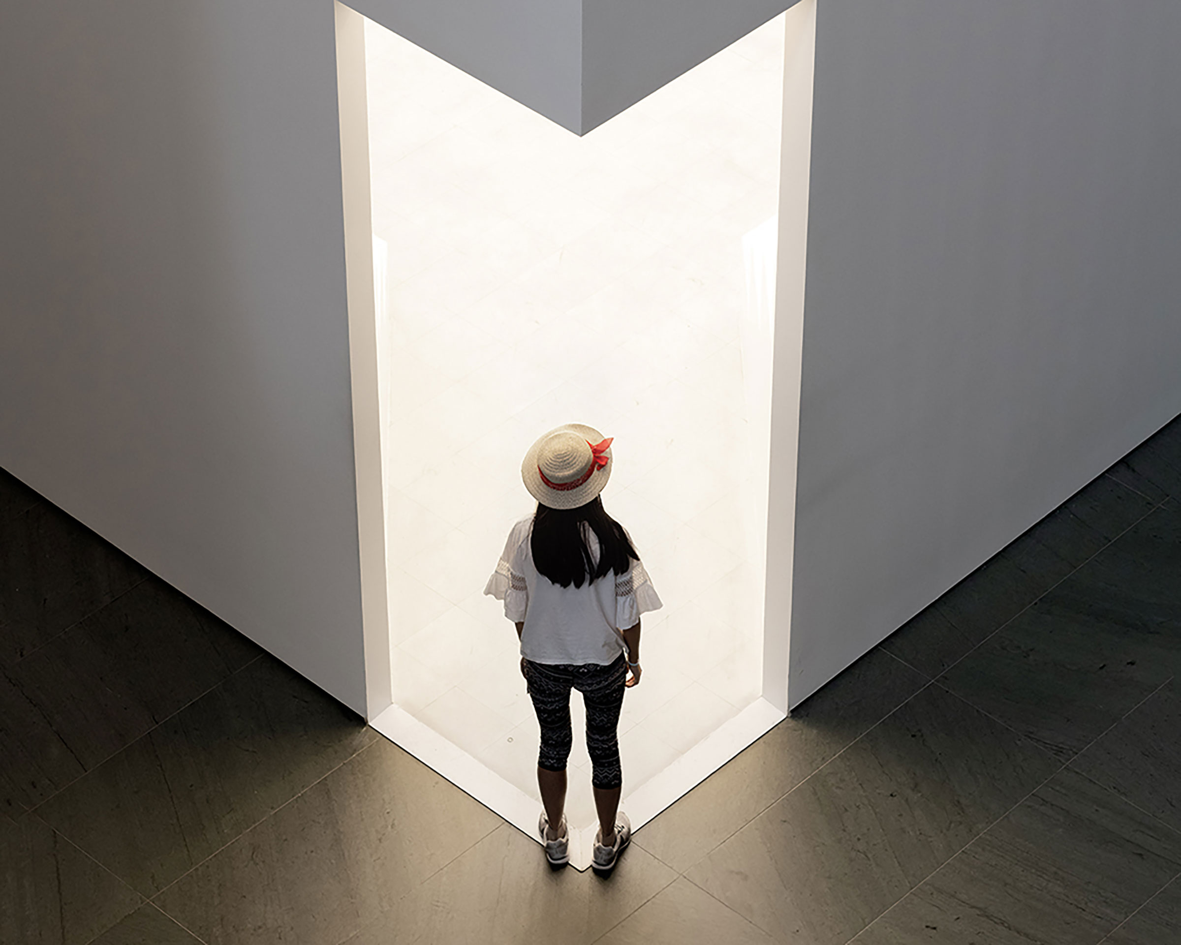 A woman stands at the threshold of an illuminated doorway