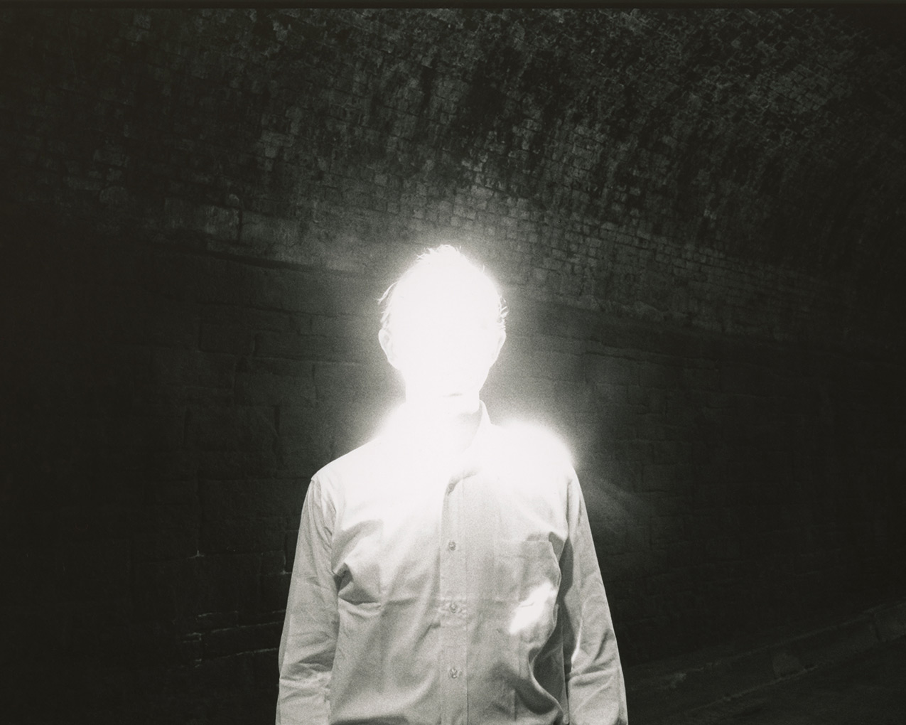 A human figure is depicted wit its facial features obscured by high-exposure light