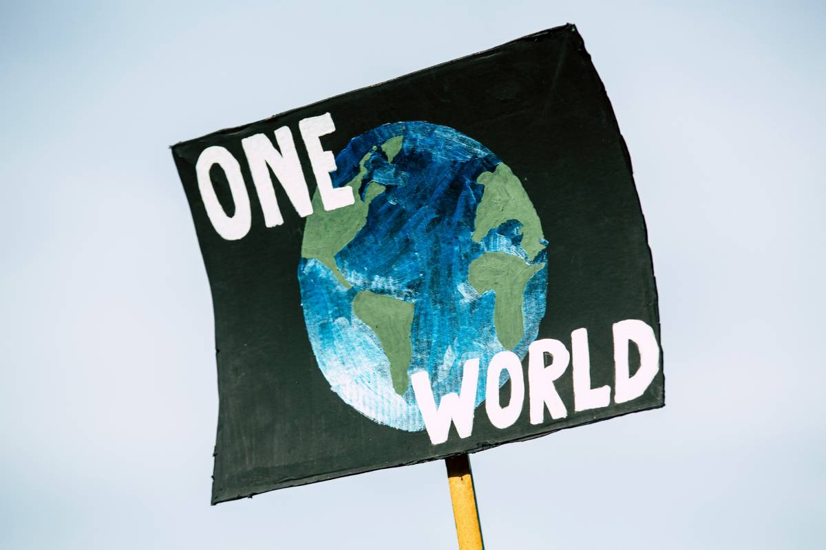 Photo of a placard with "One World" written with the Earth.