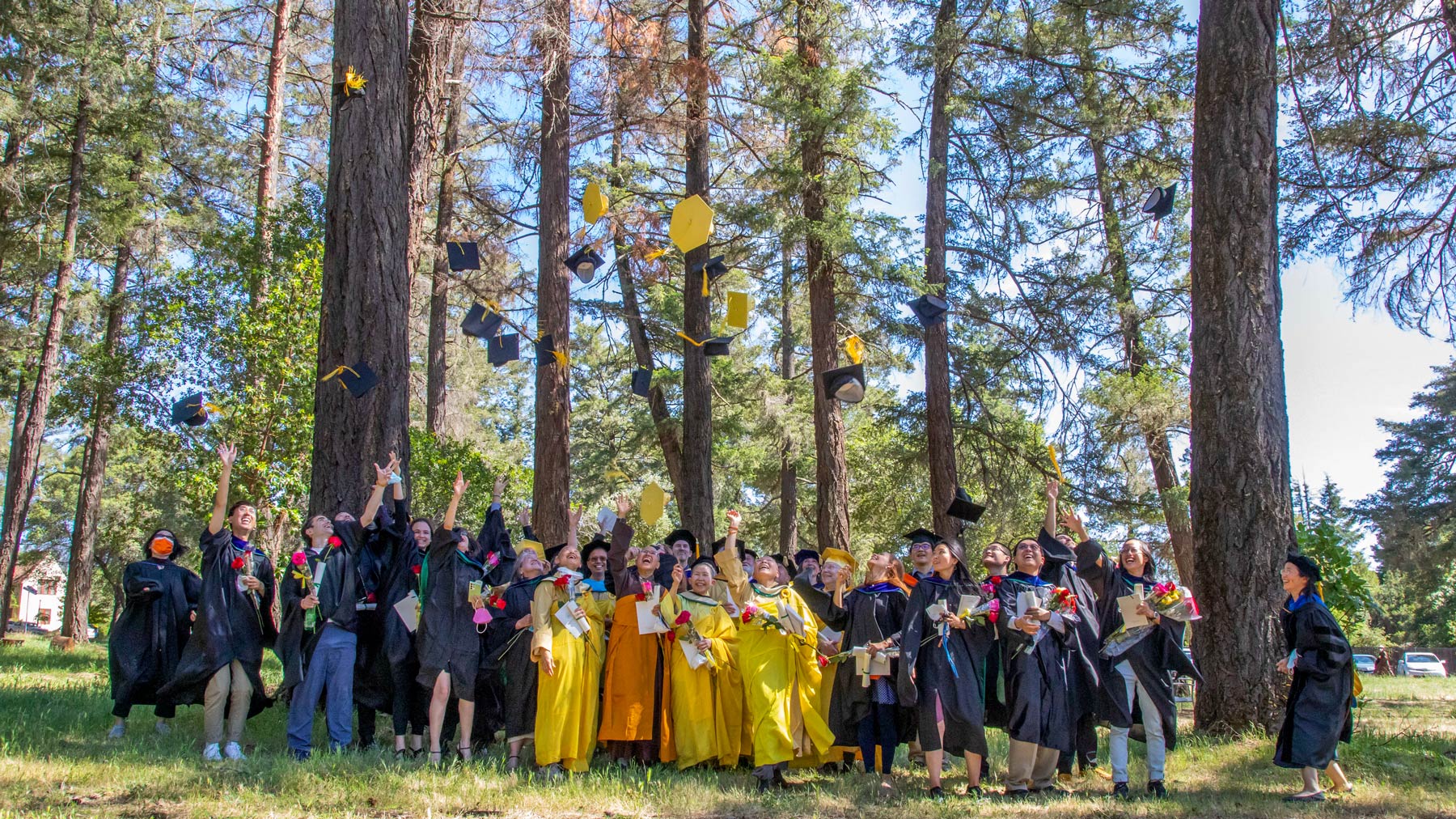 Dharma Realm Buddhist University’s graduating class of 2022 throw their caps in the air.