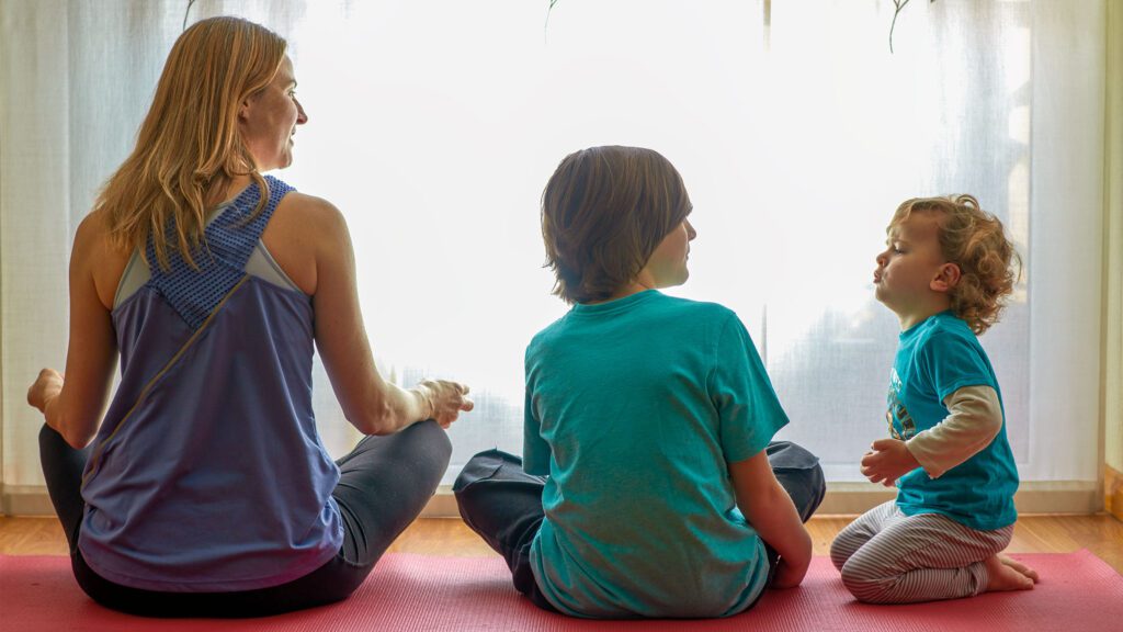 Mother and children sitting cross-legged meditating.