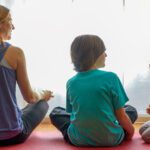 Mother and children sitting cross-legged meditating.