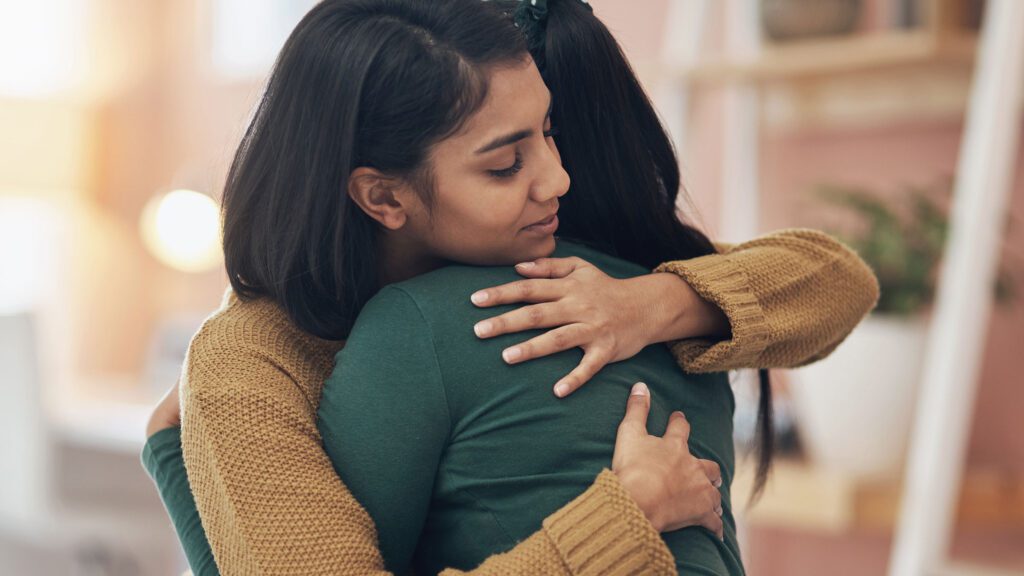 Two women embracing each other.
