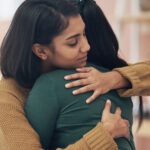 Two women embracing each other.